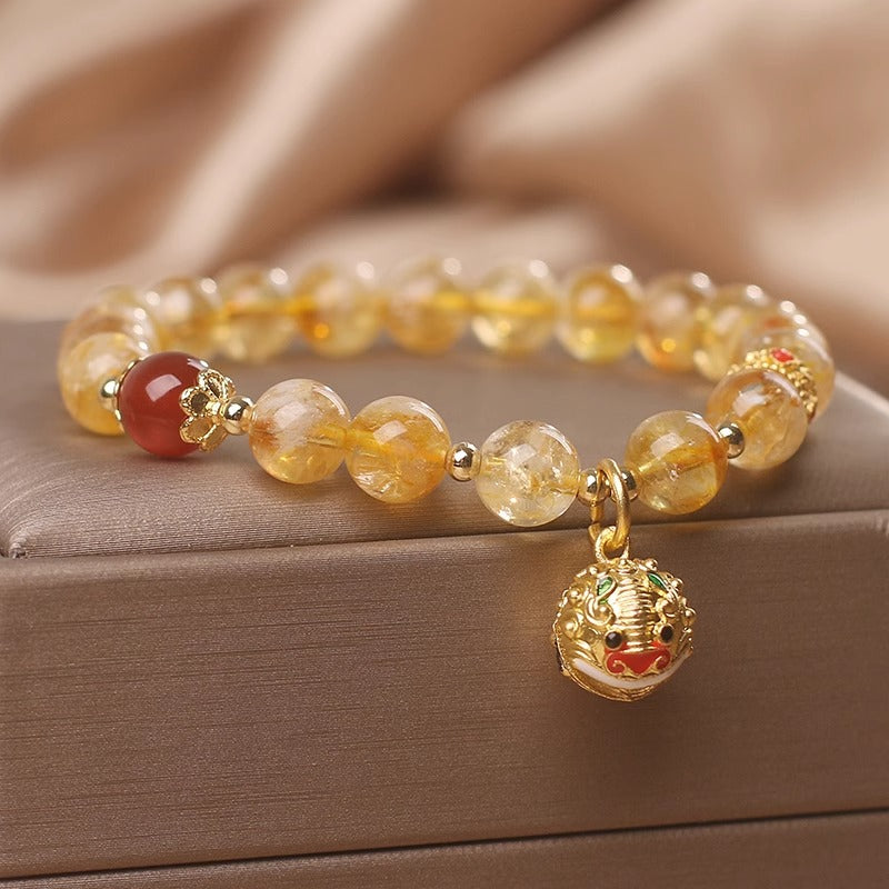 Bracelet with yellow beads and a gold charm on a wooden surface