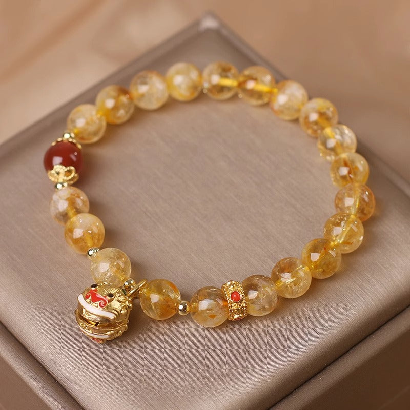 Beaded bracelet with gold charms on a beige surface
