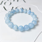 Blue beaded bracelet on a white surface with blurred text in the background