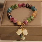 Multicolored beaded bracelet with a gold charm on a brown surface